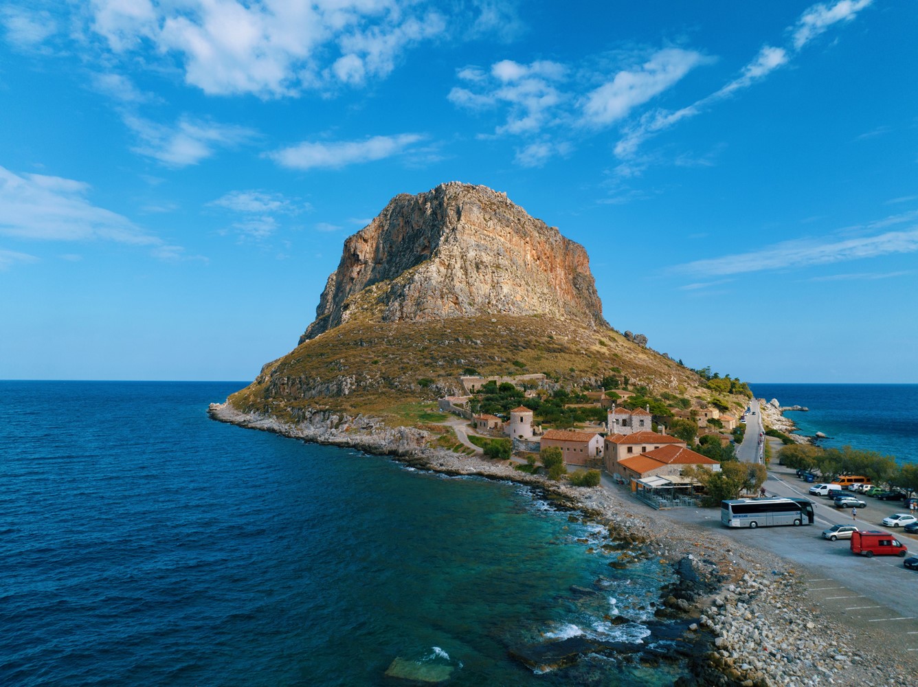 A towering rock on the sea surrounded by a small town
