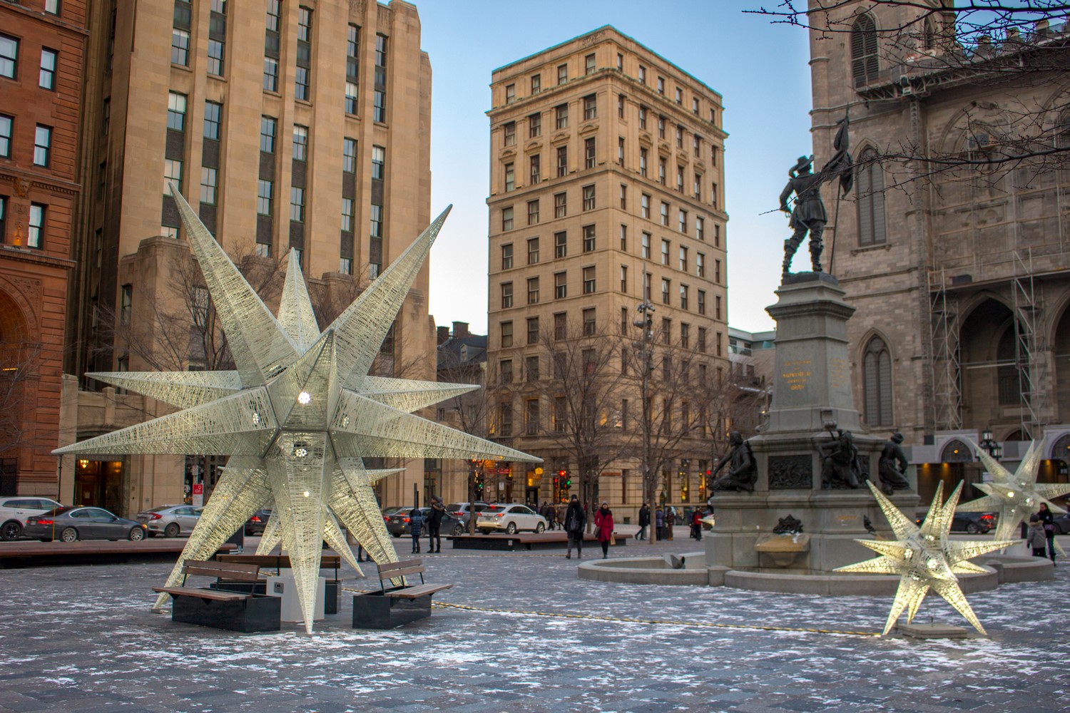 Large illuminated star decorations displayed in a snowy plaza