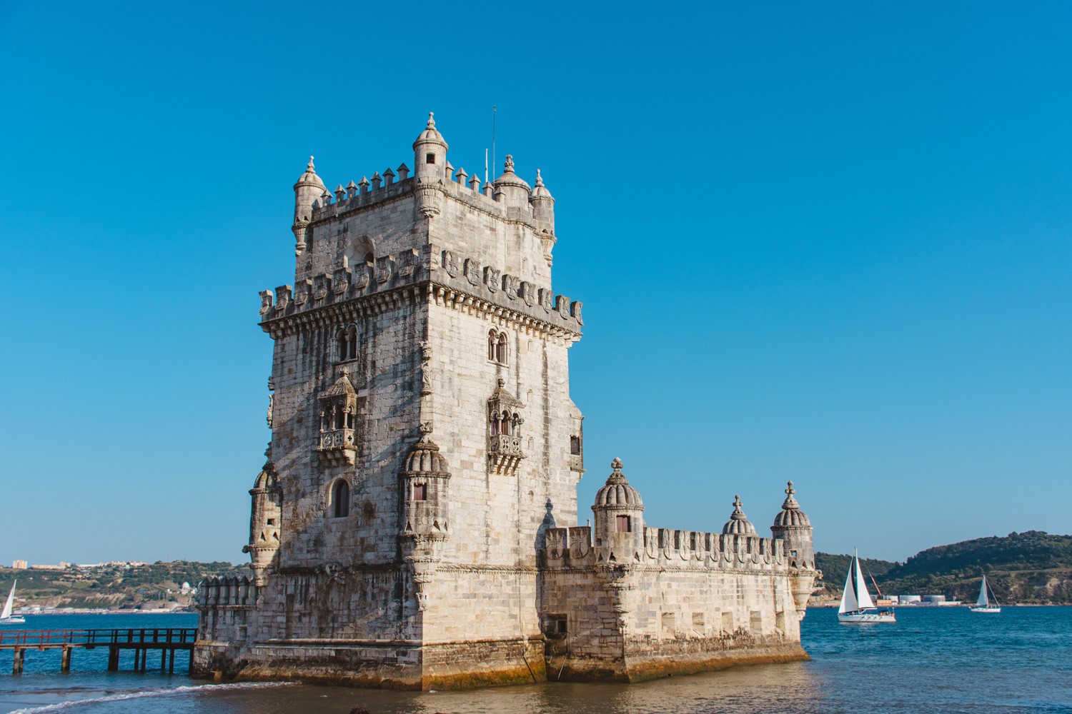 Historic stone tower on the water with sailboats nearby